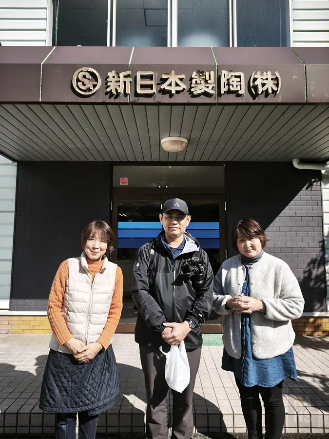 翰斯與新日本製陶工作人員於招牌前合影留念