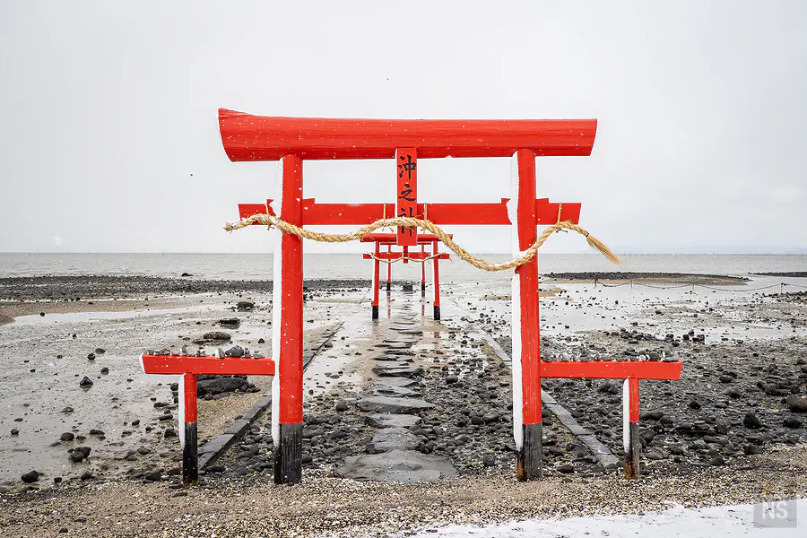 雪中退潮石板參道通往海中鳥居下方水墨般畫面