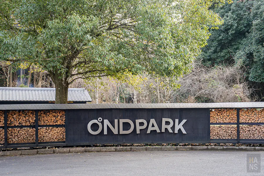 ONDPARK招牌近照，牆面堆滿薪火桑拿用的柴薪