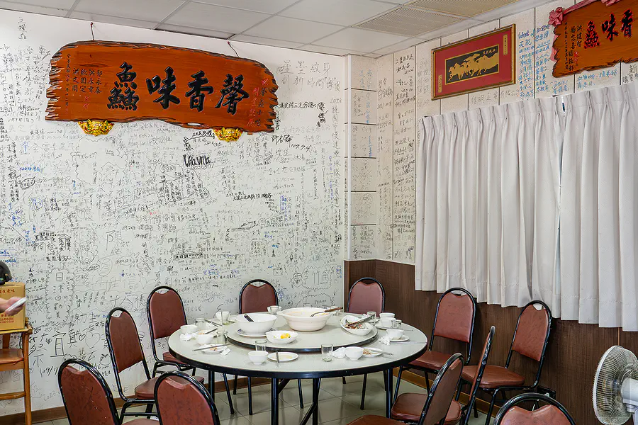 隘門馨鱻小館內滿滿顧客簽名的特色牆面與用餐大圓桌
