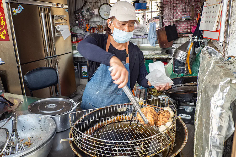 老闆娘熟練地將豐富內餡鋪滿勺子,準備下鍋油炸的誘人畫面