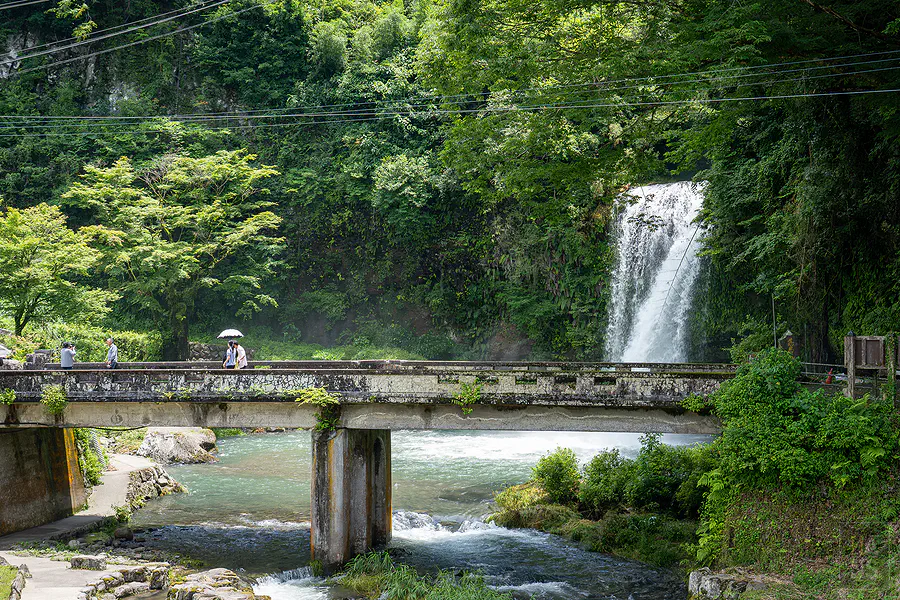 慈恩瀑布前古樸石橋與撐傘旅人