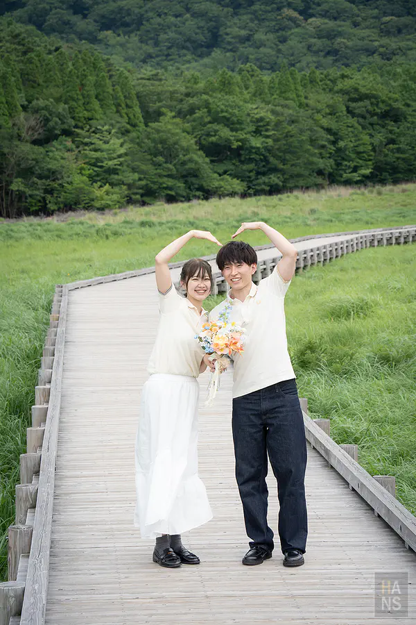 蓼原濕原木道上新人比出愛心手勢的婚紗紀念照