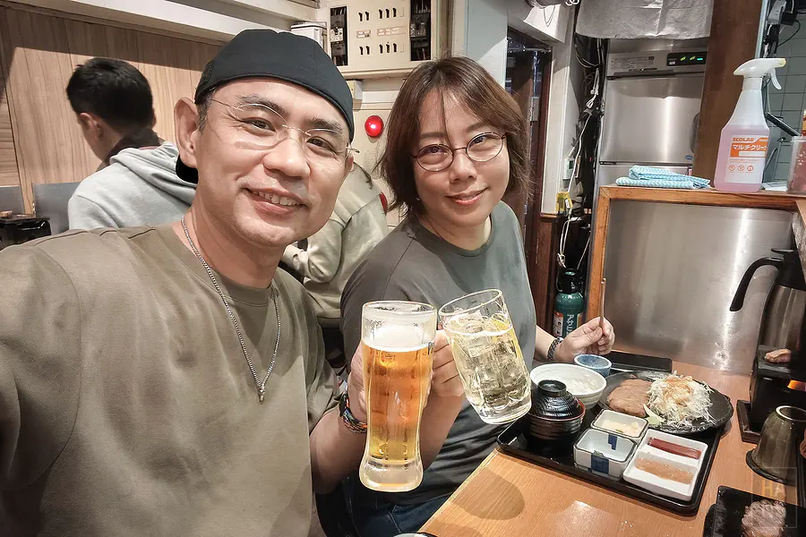 翰斯穿咖啡色 T-shirt 配戴 AWNL 隕石項鍊在東京居酒屋與 Kay 舉杯
