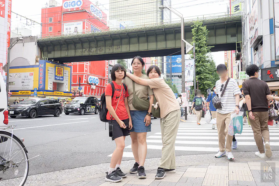 Kay 與兩個女兒在秋葉原街頭路口合照，背景為 GiGO 電玩中心招牌