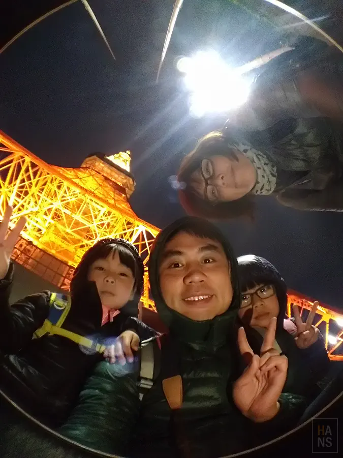 翰斯一家四口在夜間東京鐵塔下用魚眼鏡頭自拍合照