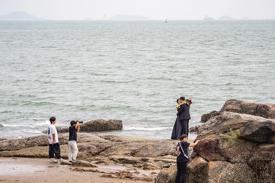 新人在鼓浪嶼海邊礁石上拍攝婚紗