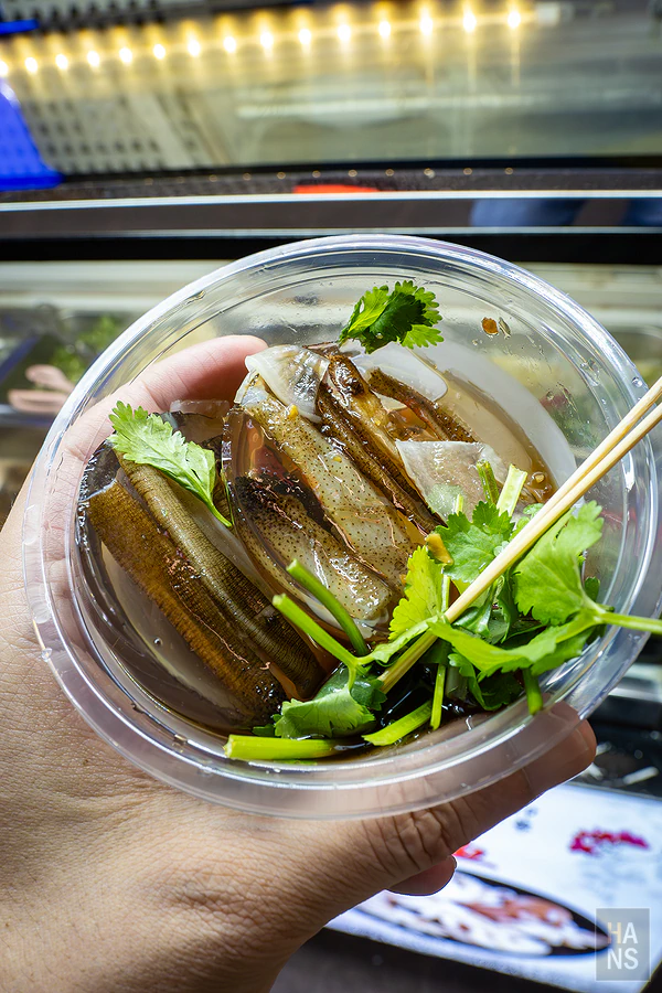 拿在手上準備品嚐的土筍凍，上頭撒了新鮮香菜與特製醬汁